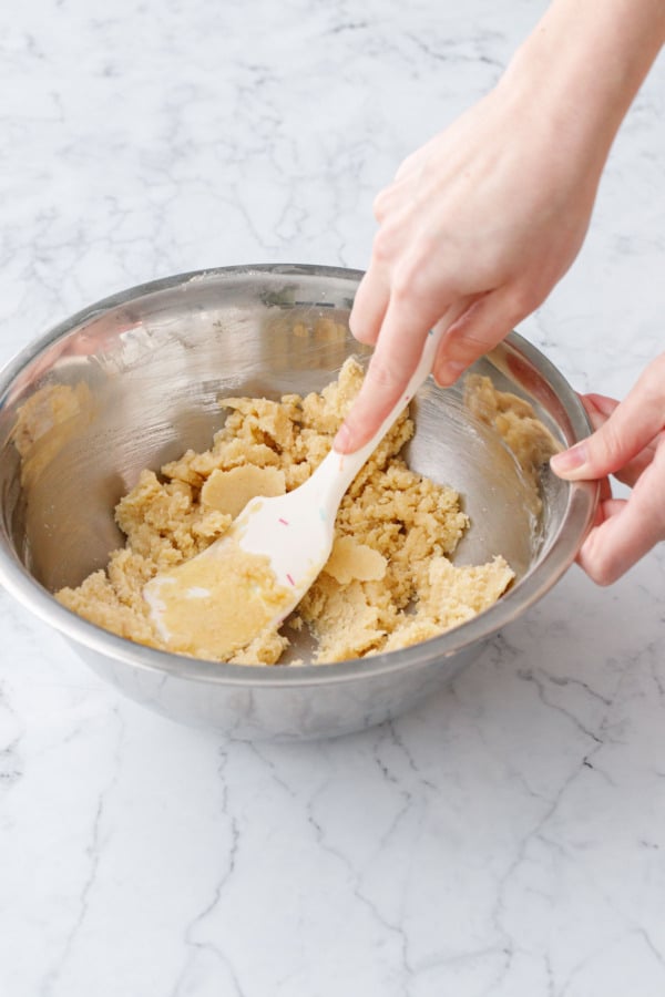 Stirring melted butter into dry ingredients with a silicone spatula.