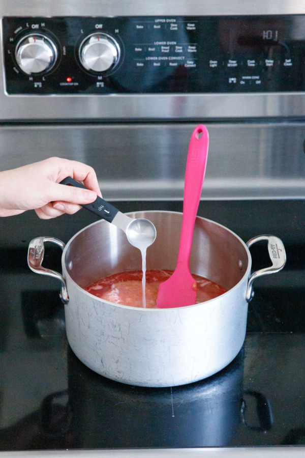 Pouring calcium water into saucepan along with fruit.
