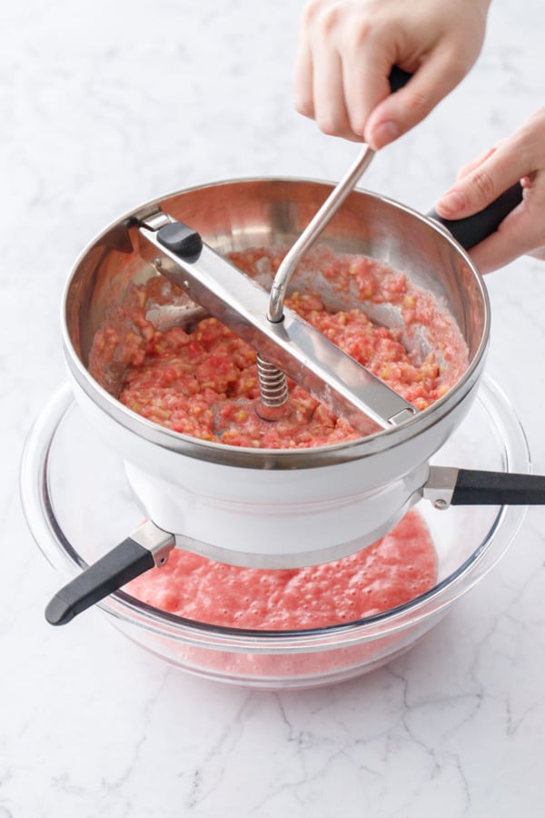 Processing guava puree through a fine screen food mill to make smooth guava puree.