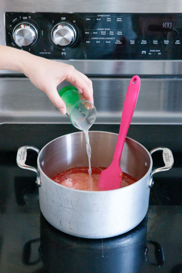 Pouring lemon juice into saucepan along with fruit.