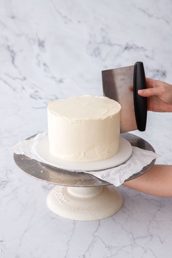 Get smooth buttercream sides by using a flat-edged pastry scraper while spinning the cake on a turntable.