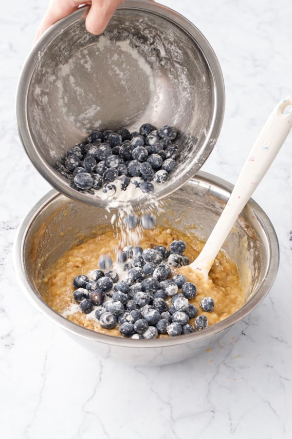 Pouring flour-coated blueberries into mixing bowl with just-combined batter.