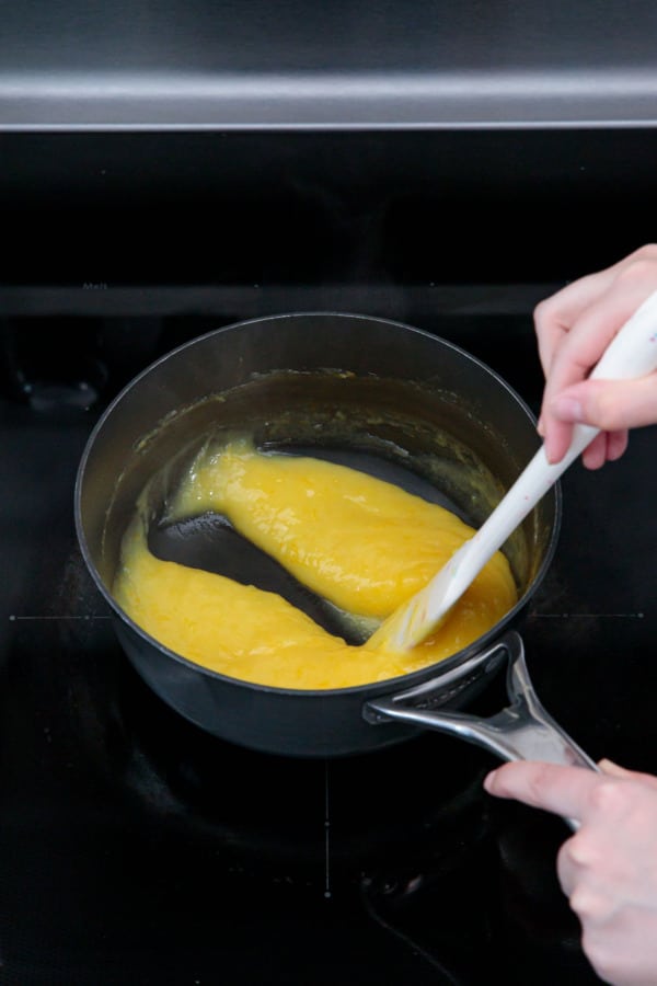 Spatula leaving a trail through the cooked curd that doesn't fill in on itself, meaning the curd is done.