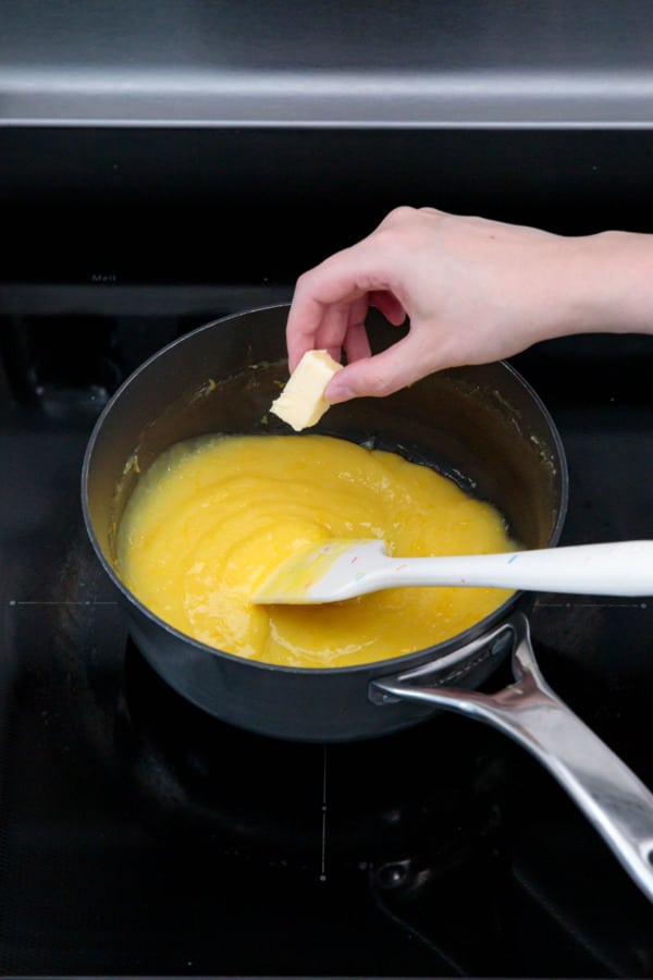 Adding one piece of butter to the cooked curd off the heat.