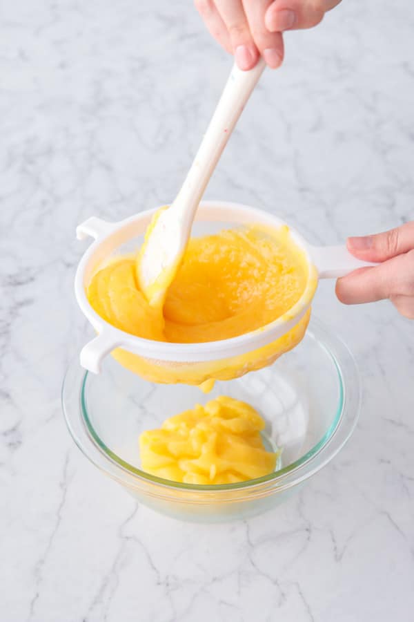 Pressing the lemon curd through a nylon mesh sieve to remove bits of zest and cooked egg.