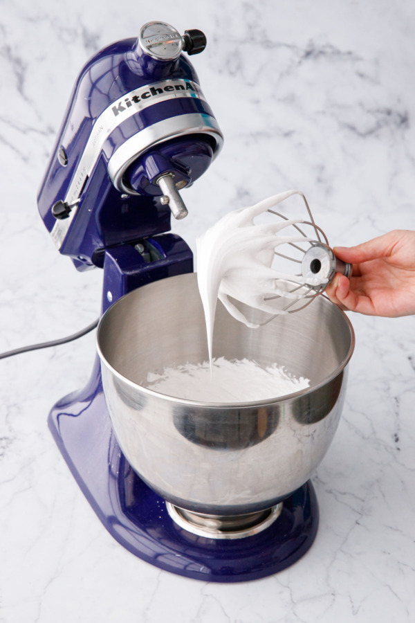 Whisk attachment showing soft peaks of meringue with a point that droops over itself.