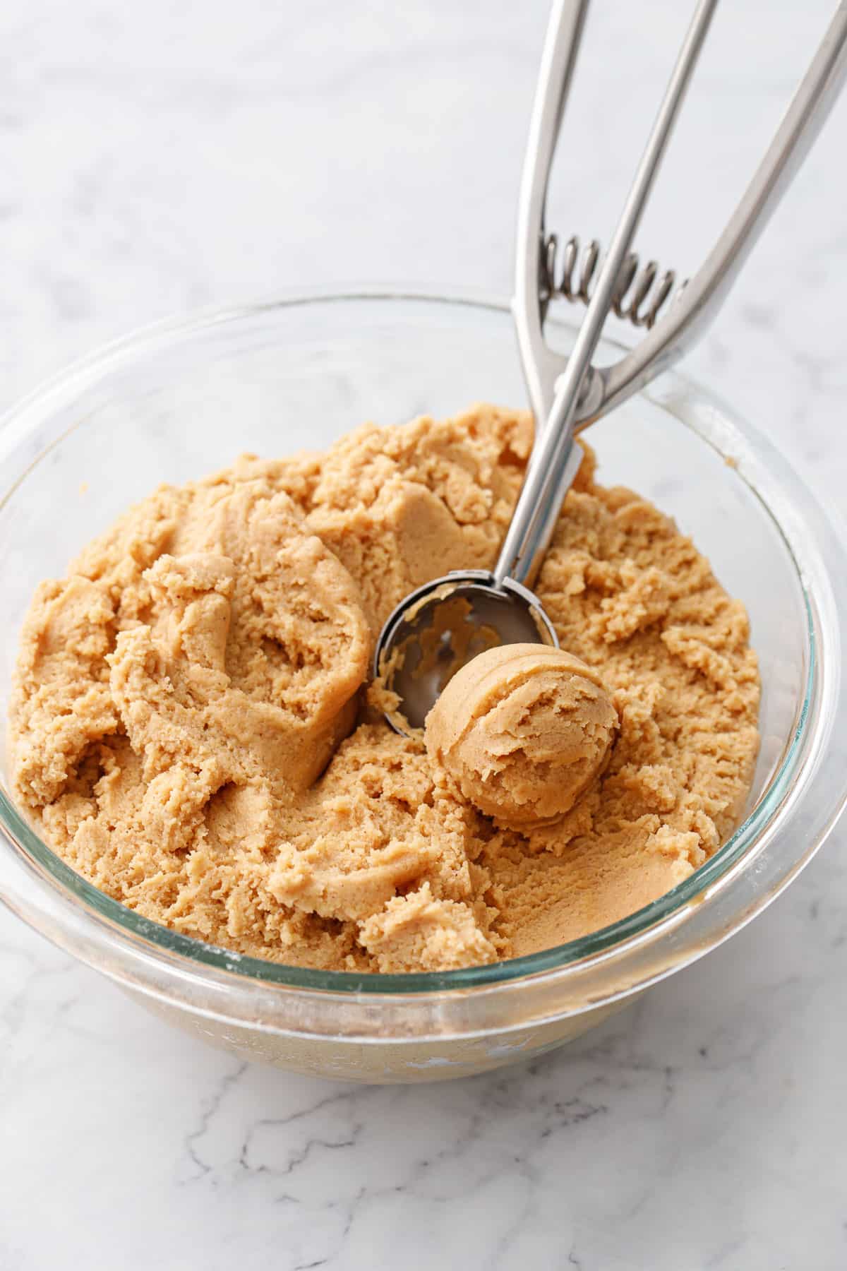 Bowl of peanut butter thumbprint cookie dough in a glass bowl.