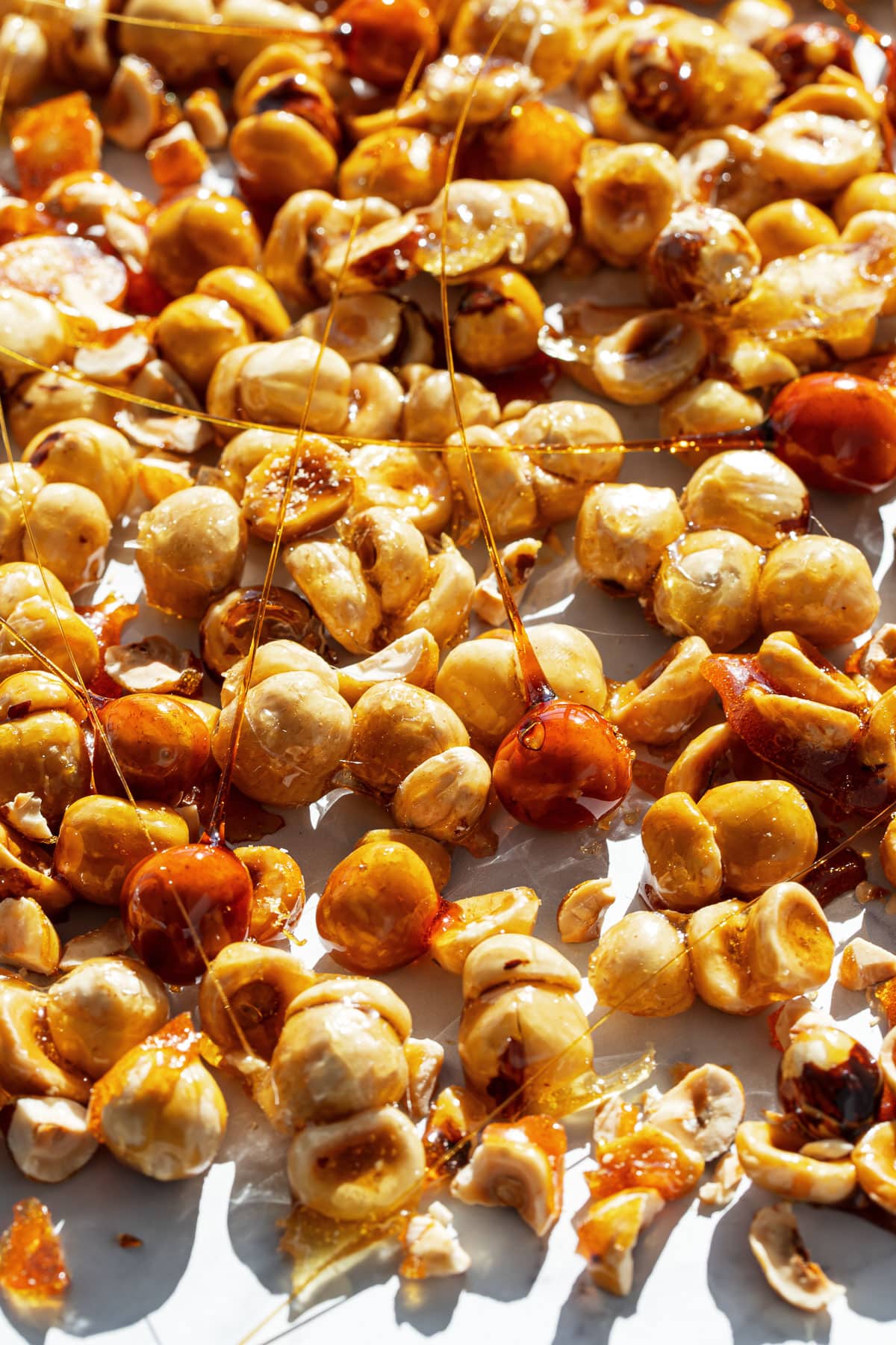 Scattered Caramelized Candied Hazelnuts (Clusters and Spikes) messily spread on a parchment background.
