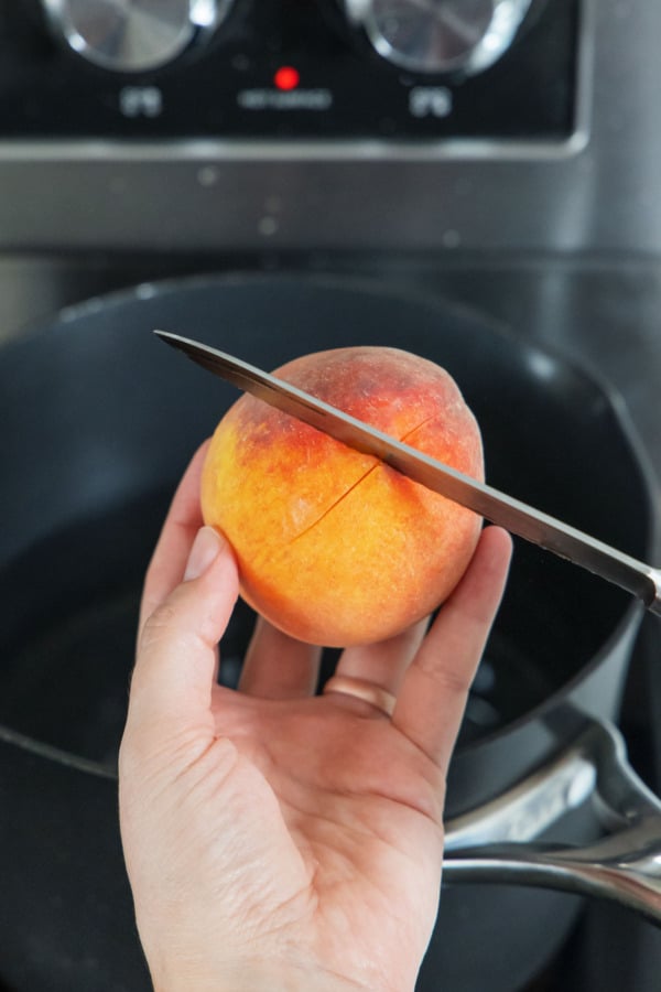 Cutting an X in the bottom of a fresh peach.