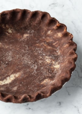 Closeup of the fluted edge of an unbaked chocolate pie crust.