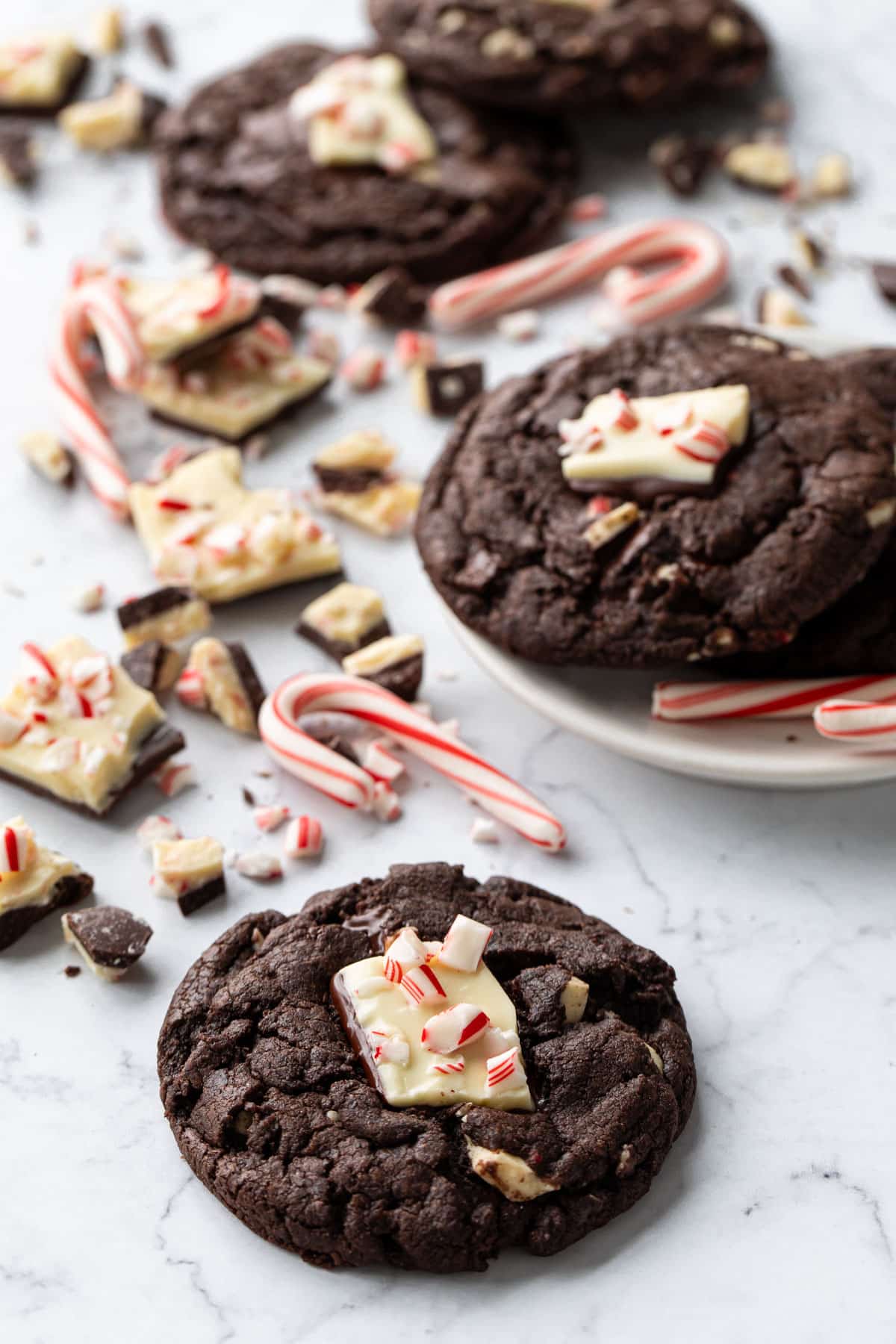 Chocolate Peppermint Bark Cookies on a marble background, with candy canes and broken bits of peppermint bark scattered around.
