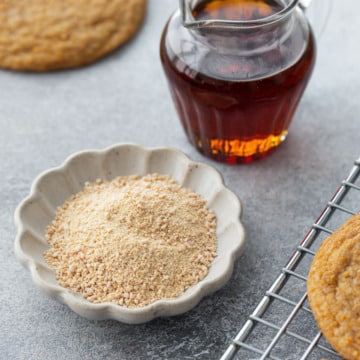 Small glass pitcher with maple syrup, and a small fluted bowl with maple sugar.