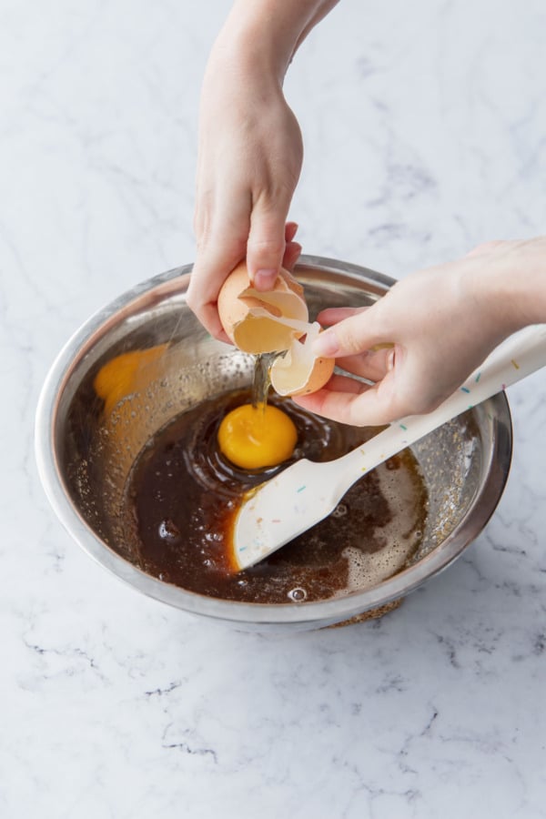 Cracking an egg into the mixing bowl with the other ingredients.