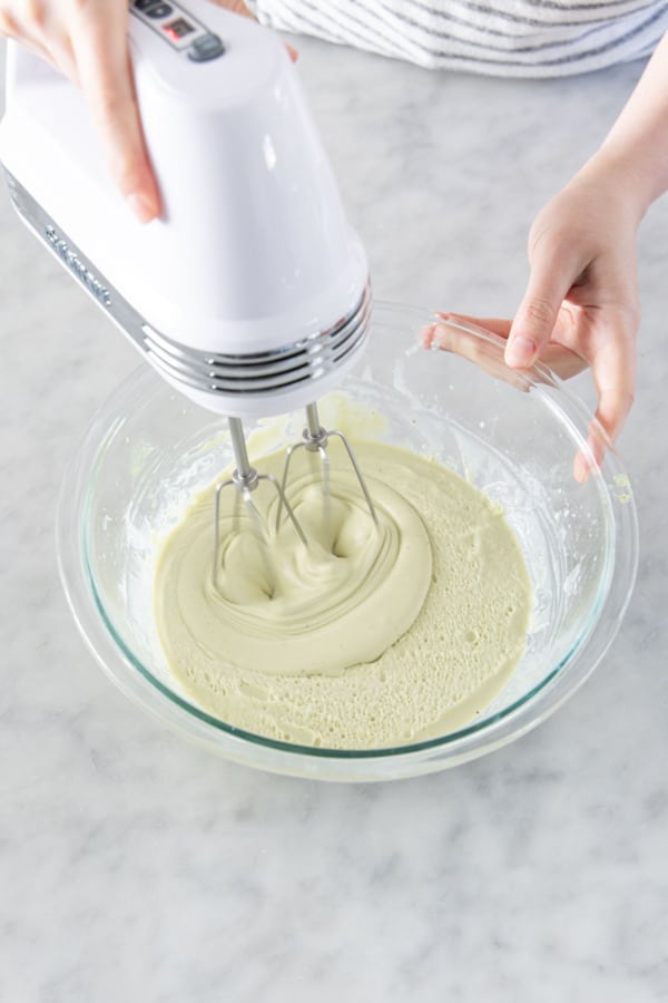 Beating pistachio whipped ganache with an electric hand mixer.