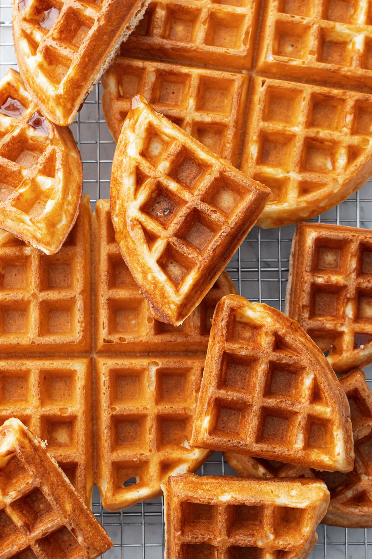 Golden brown Sourdough Discard Waffles arranged haphazardly on a wire baking rack.