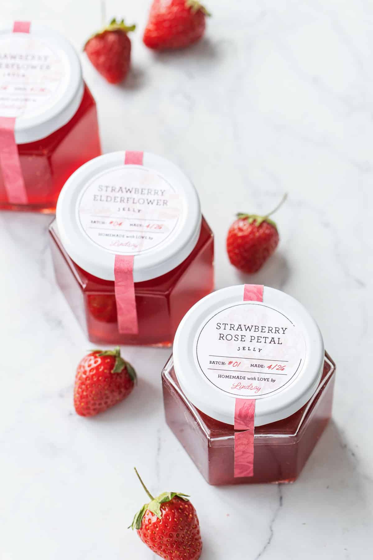 Three jars of Strawberry Elderflower Jelly and Strawberry Rose Jelly with beautifully designed printable labels on the lids.