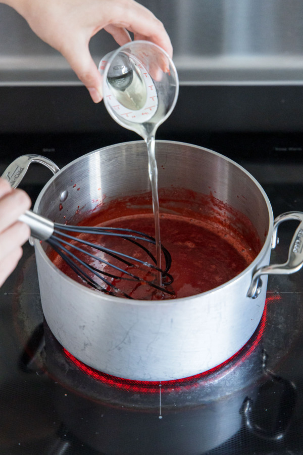 Pouring in elderflower syrup to flavor the strawberry jelly.