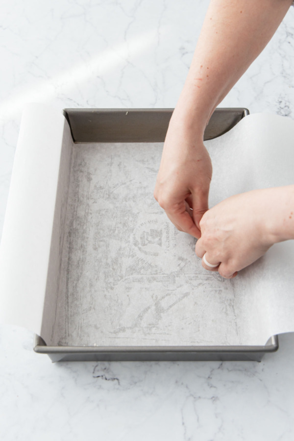 Lining a buttered baking pan with parchment paper.