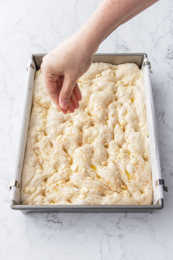 Sprinkling final focaccia with flaky salt and turbinado sugar before baking.