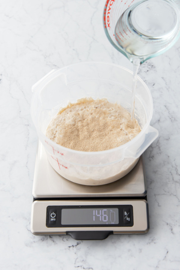 Adding water to the poolish mixture.