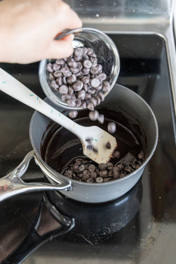 Adding semisweet chocolate pieces to the saucepan to melt.