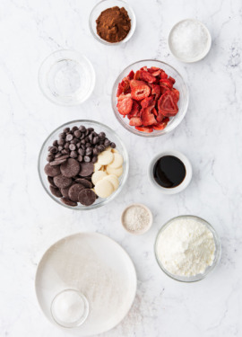 Overhead flatlay on a marble background with bowls of varying sizes filled with different ingredients.