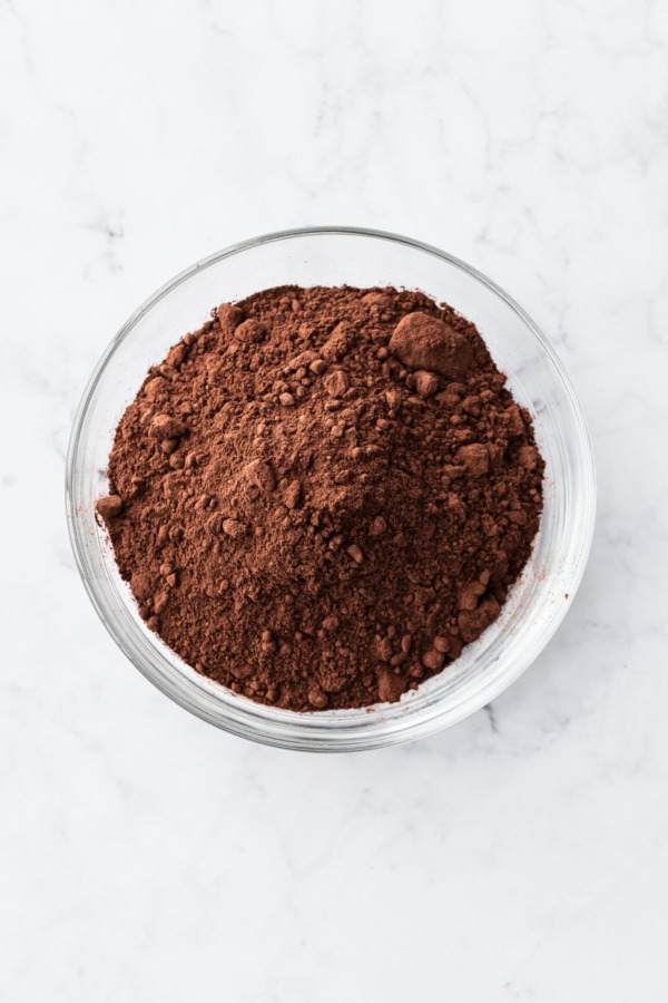 Bowl of Dutch-process cocoa powder in a clear bowl on a marble background.