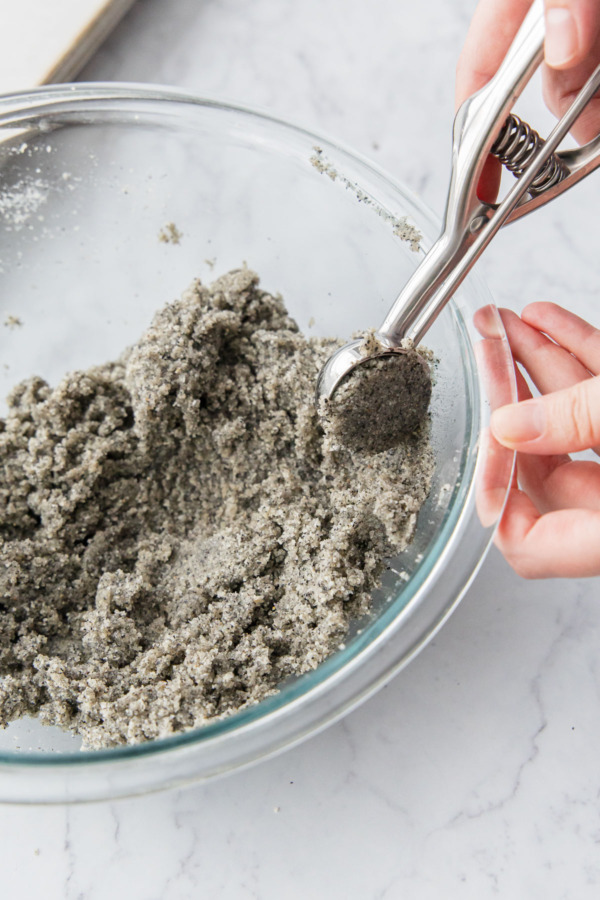 Small cookie scoop scooping small balls of black sesame dough.