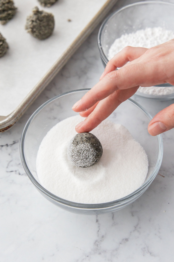 Rolling the shaped dough ball in granulated sugar.