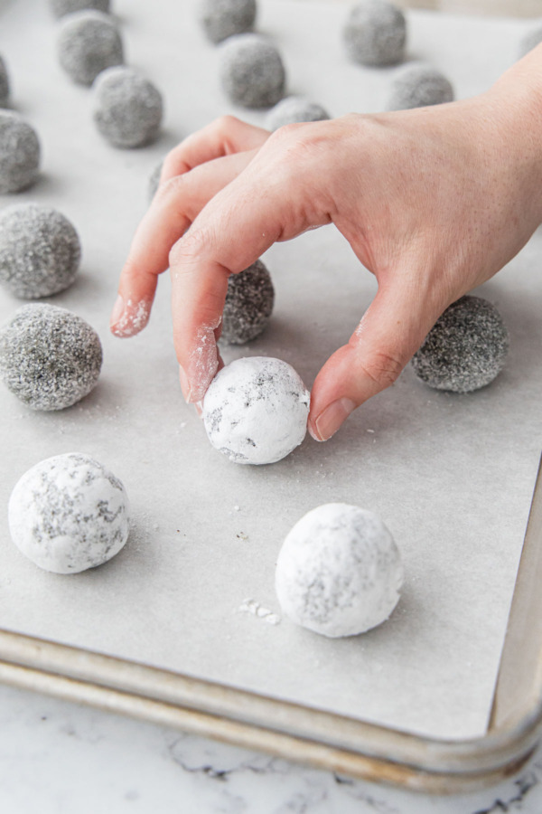Arranging sugar-coated dough balls on a parchment-lined baking sheet.