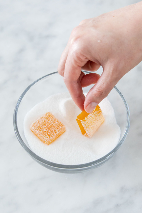Rolling set pate de fruit jellies in granulated sugar until fully coated.