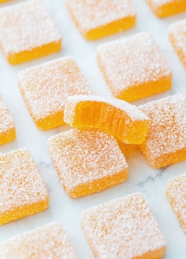 Passionfruit Jellies (Pate de Fruit) coated in granulated sugar, a bite out of one piece to show the jammy texture inside.