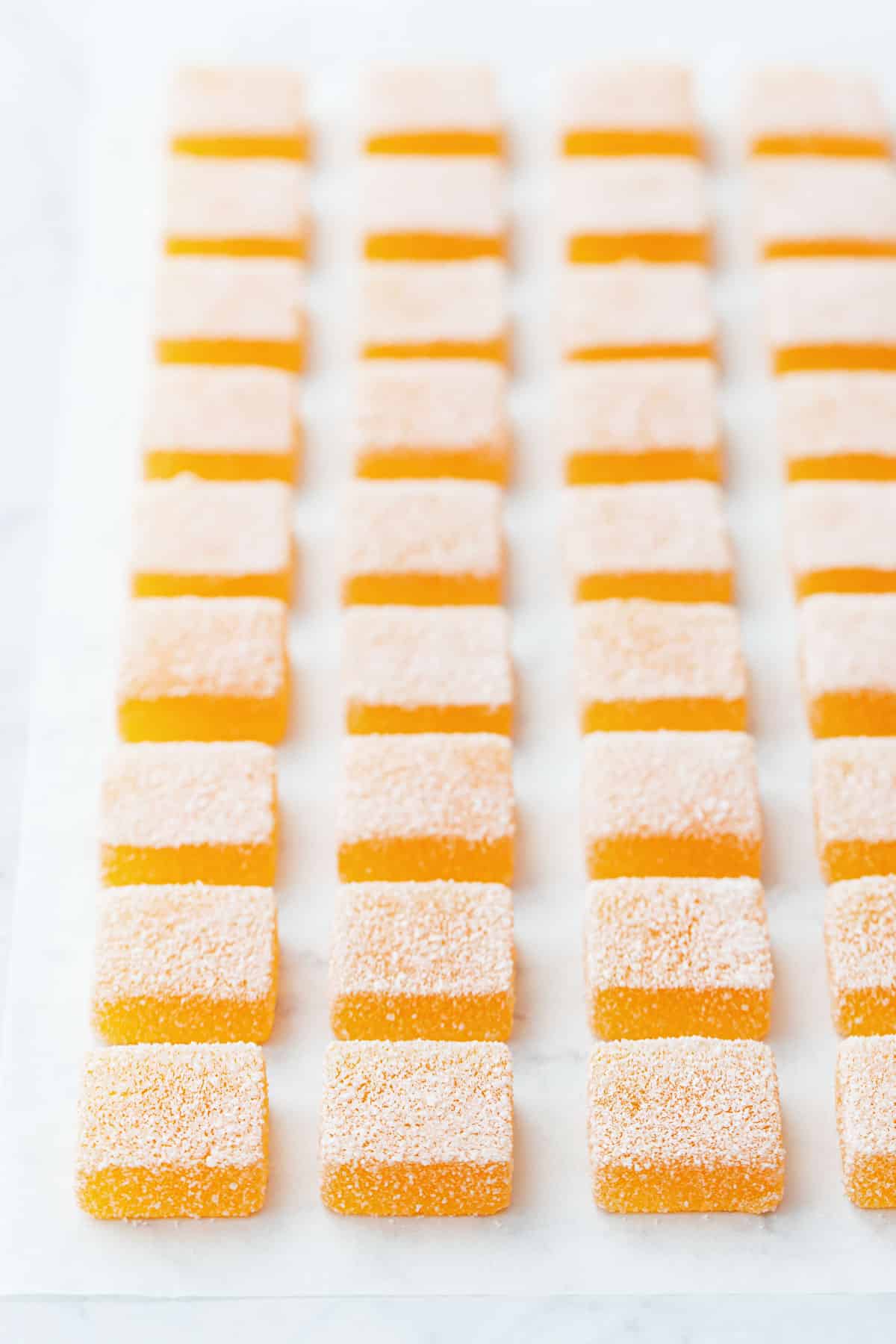 Neat rows of Passionfruit Jellies (Pate de Fruit) on a white parchment background.