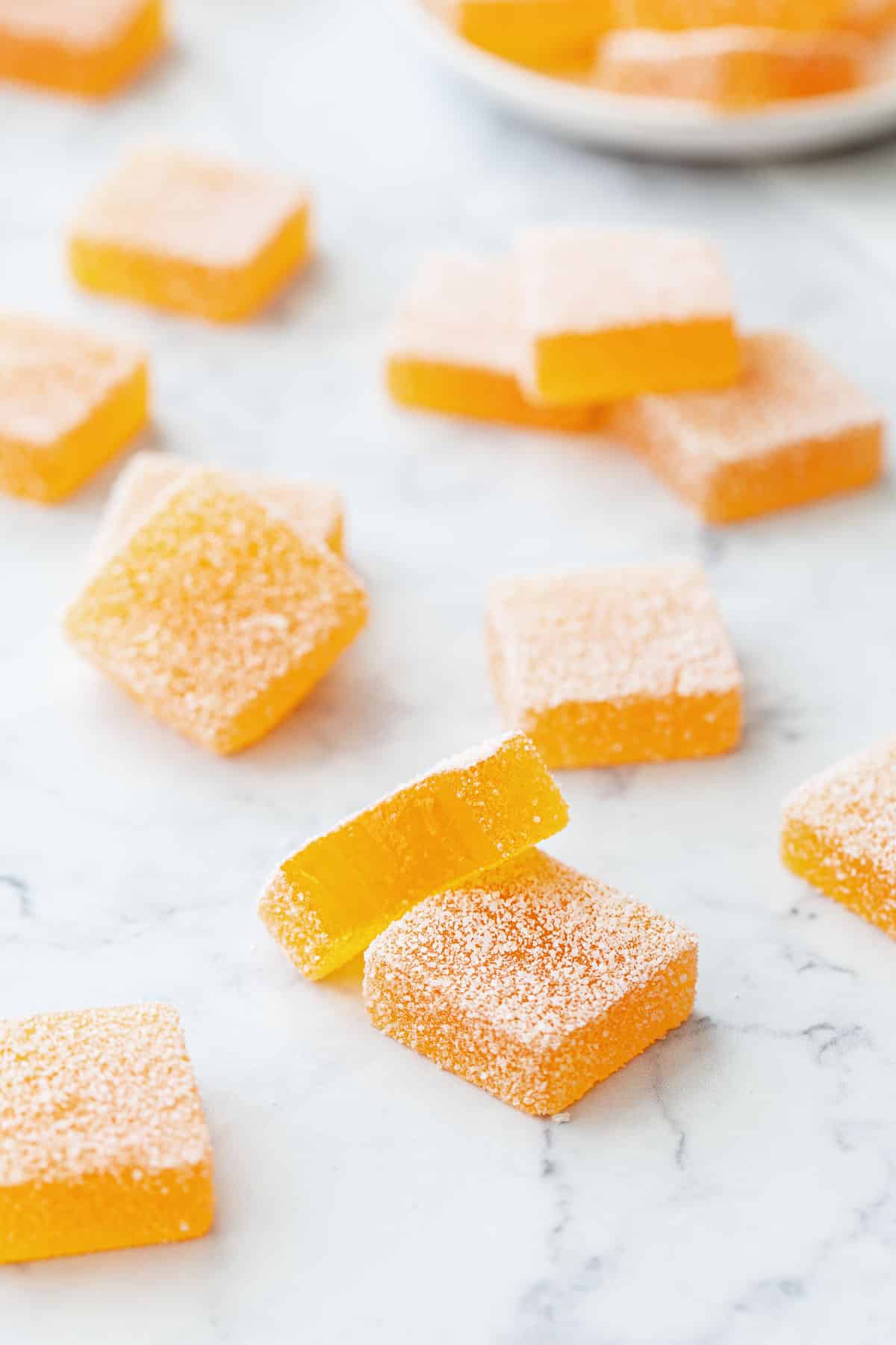 Passionfruit Jellies (Pate de Fruit) on a marble background, a bite taken out of one piece to show the interior texture.