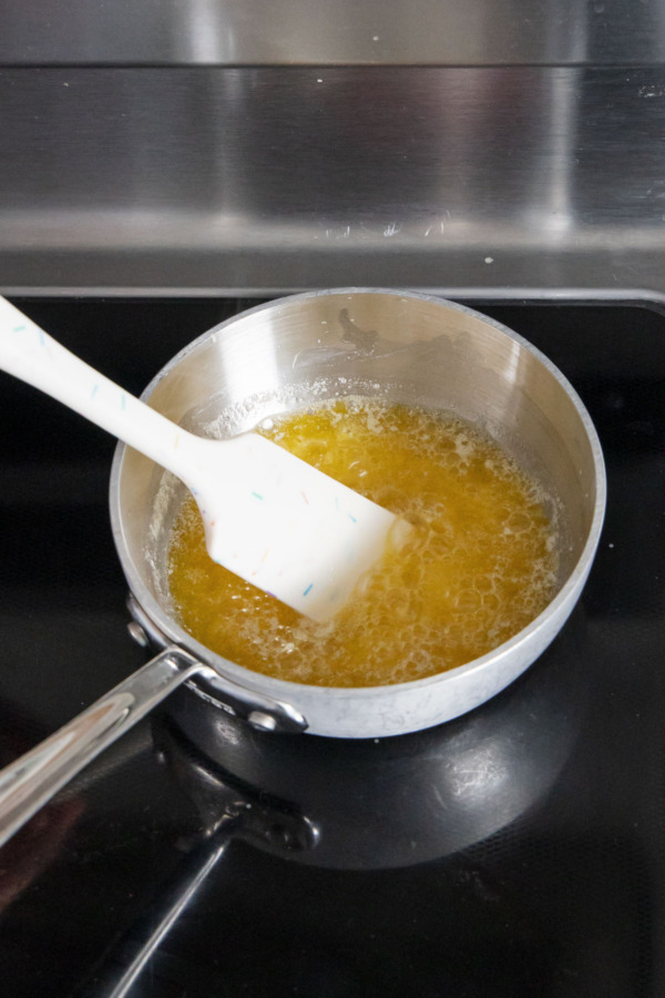 Melted butter bubbling in a small stainless saucepan with rubber spatula.