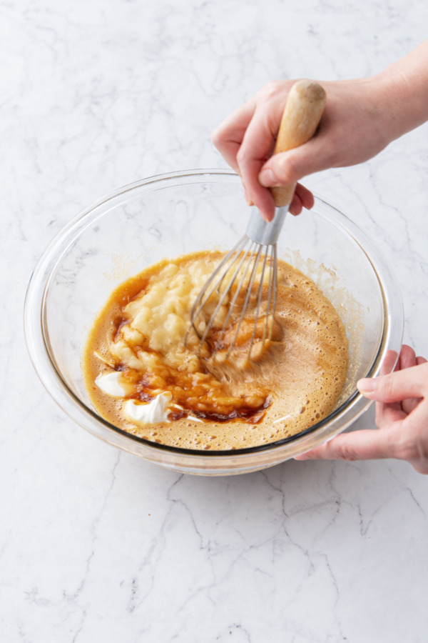 Whisking wet ingredients in a glass mixing bowl until evenly combined.
