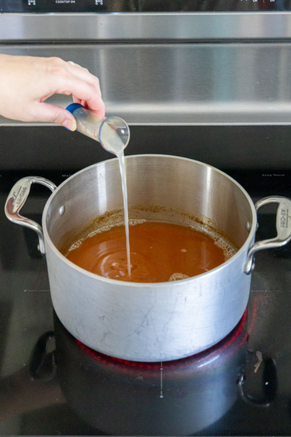 Adding lemon juice and calcium water to saucepan with apple cider.
