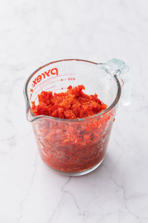 Measuring cup filled with finely chopped peppers.