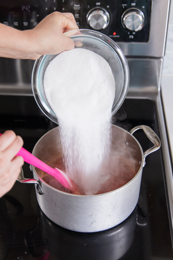 Adding remaining 2 cups of sugar to saucepan with simmering pepper mixture.